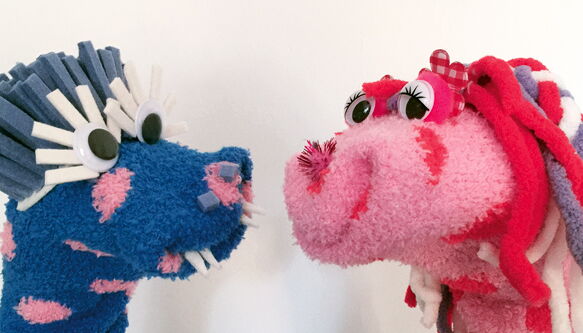 Ein blaues und ein rosa Monster, die aus Socken gebastelt sind.