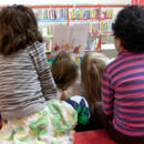 Kinder sehen sich gemeinsam mit einem Erwachsenen ein Buch an