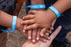 Kinderhände mit UNICEF-Armband die sich anfassen