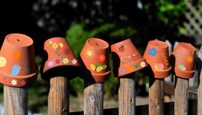 Bunt bemalte Blumentöpfe auf einem Holzzaun