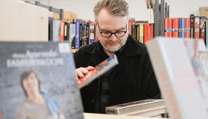 Mann stöbert in Bücherflohmarkt
