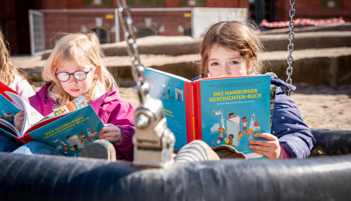 zwei Mädchen mit Buch in Schaukel