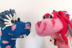 Ein blaues und ein rosa Monster, die aus Socken gebastelt sind.