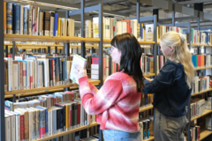 Zwei Personen stöbern Bücher in der Zentralbibliothek