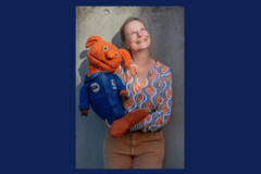 Frau mit oranger Handpuppe im Weltall-Anzug