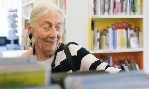 ältere Dame stöbert in der Bücherhalle