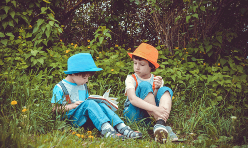 zwei Kinder lesen im Park
