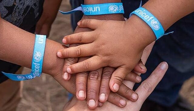 Kinderhände mit UNICEF-Armband die sich anfassen