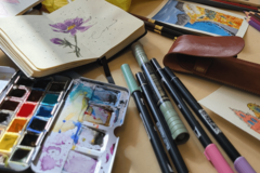 Aquarell-Palette, Notizbuch mit Blumenzeichnung und Stifte
