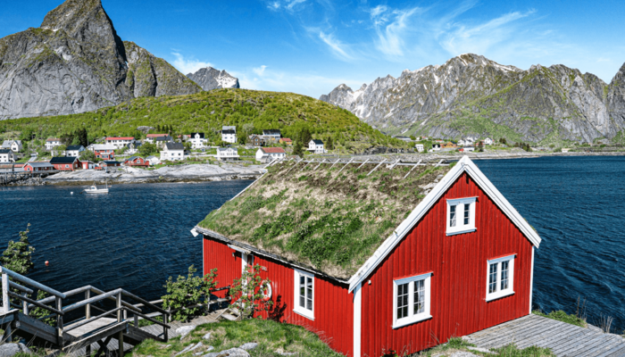 Rotes, nordisches Haus mit Bergen und Meer im Hintergrund