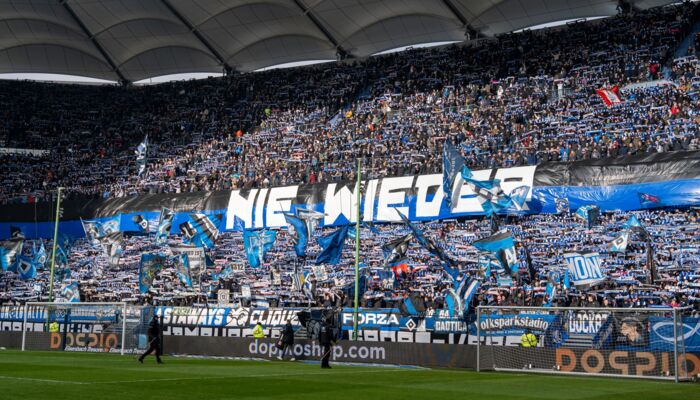 Nordtribüne des HSV zeigt Einen schwarz-blauen Banner mit weißer Aufschrift in Großbuchstaben: NIE WIEDER