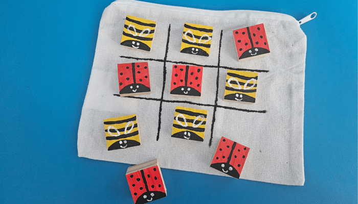 Tic-Tac-Toe-Spiel aus Holzblöcken, die als Bienen und Marienkäfer gestaltet sind.