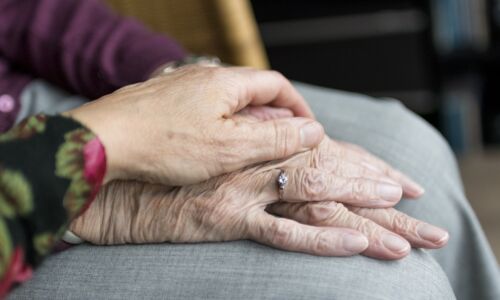 Bild zeigt eine tröstende, unterstützende Hand auf die Hand eines älteren Menschen gelegt