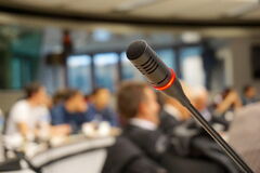 Foto eines Mikrofons mit Publikum im Hintergrund