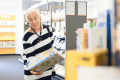 ältere Dame stöbert in der Bücherhalle