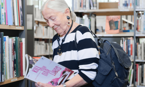 ältere Dame stöbert in der Bücherhalle