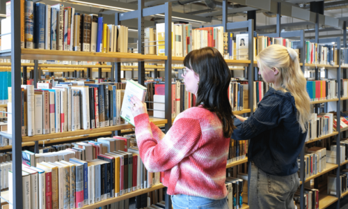 Zwei Personen stöbern Bücher in der Zentralbibliothek