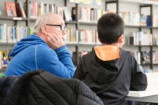 Mann hilft Kind beim Lesen lernen in der Bücherhalle