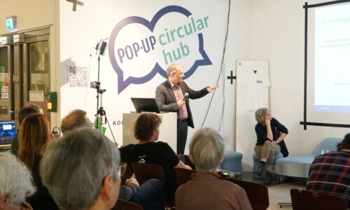 Mann am Rednerpult zeigt eine Präsentation