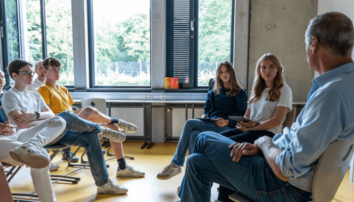 Personen sitzen im Stuhlkreis und und unterhalten sich.