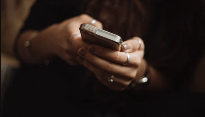 Nahaufnahme der Hände einer weiblichen Person, die ein Smartphone in ihren Händen hält.