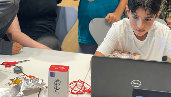 Junge sitzt vor einem Laptop und Makey Makey