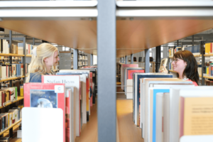 Zwei Personen stöbern Bücher in der Zentralbibliothek