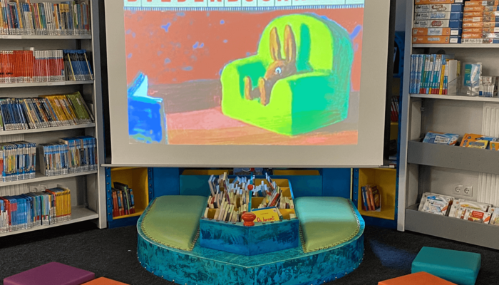 Leinwand, auf der ein Vorschaubild vom Bilderbuchkino zu sehen ist, und davor bunte Sitzkissen