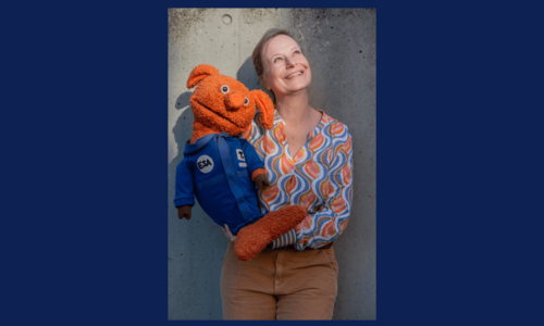 Frau mit oranger Handpuppe im Weltall-Anzug