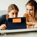 Ein Schüler und eine Schülerin blicken gemeinsam auf den Bildschirm eines Tablets.