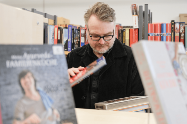 Mann stöbert in Bücherflohmarkt