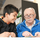 Mann hilft Kind beim Lesen lernen in der Bücherhalle