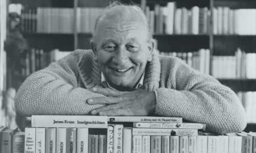 Schwarz-Weiß-Bild von James Krüss auf einem Stapel Bücher.