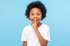 Kind, das als Zeichen zum Leisesein einen Finger an die Lippen legt