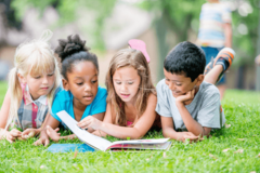 4 lesende Kinder im Gras