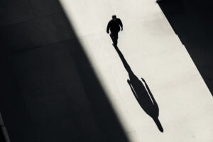 Mann im Lichtstrahl und sein Schatten in schwarz-weiss