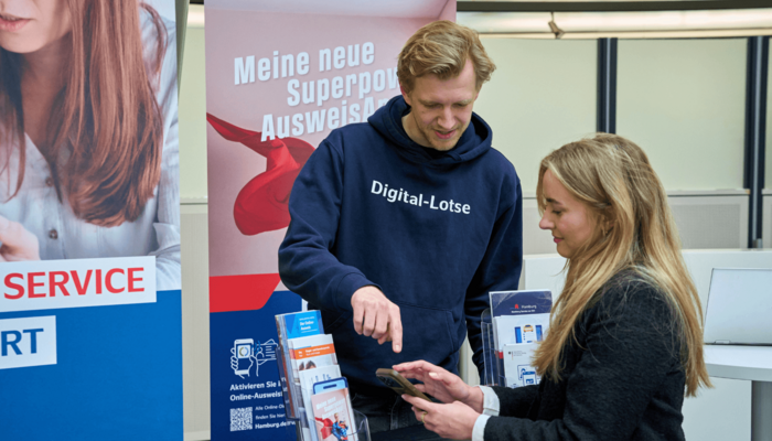 Ein Mann unterstützt eine Frau mir dem digitalen Service Angebot von Hamburg.