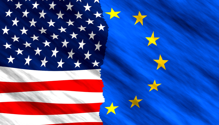 Eine Collage aus der USA-Flagge und der Europäischen Flagge. Links im Bild die USA Flagge bis zur Bildmitte, rechts davon die Europaflagge. Beide Flaggen sind nur bis etwa zur Hälfte sichtbar und ergeben als Ganzes eine zweigeteilte Flagge.