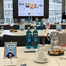 Konferenztische mit Kaffee und Wasser, im Hintergrund ein Bildschirm mit einem ePaper