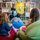 Vorlesen vor einer Kindergruppe, Bücher im Hintergrund