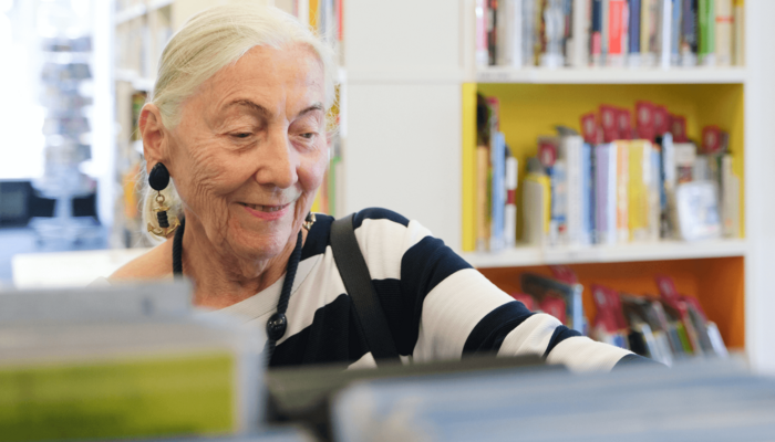 ältere Dame stöbert in der Bücherhalle