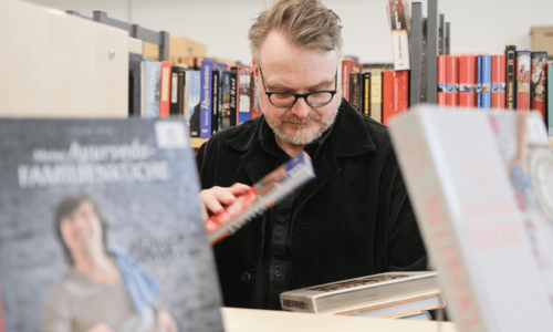 Mann stöbert in Bücherflohmarkt