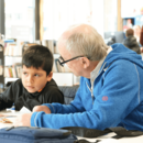 Mann hilft Kind beim Lesen lernen in der Bücherhalle