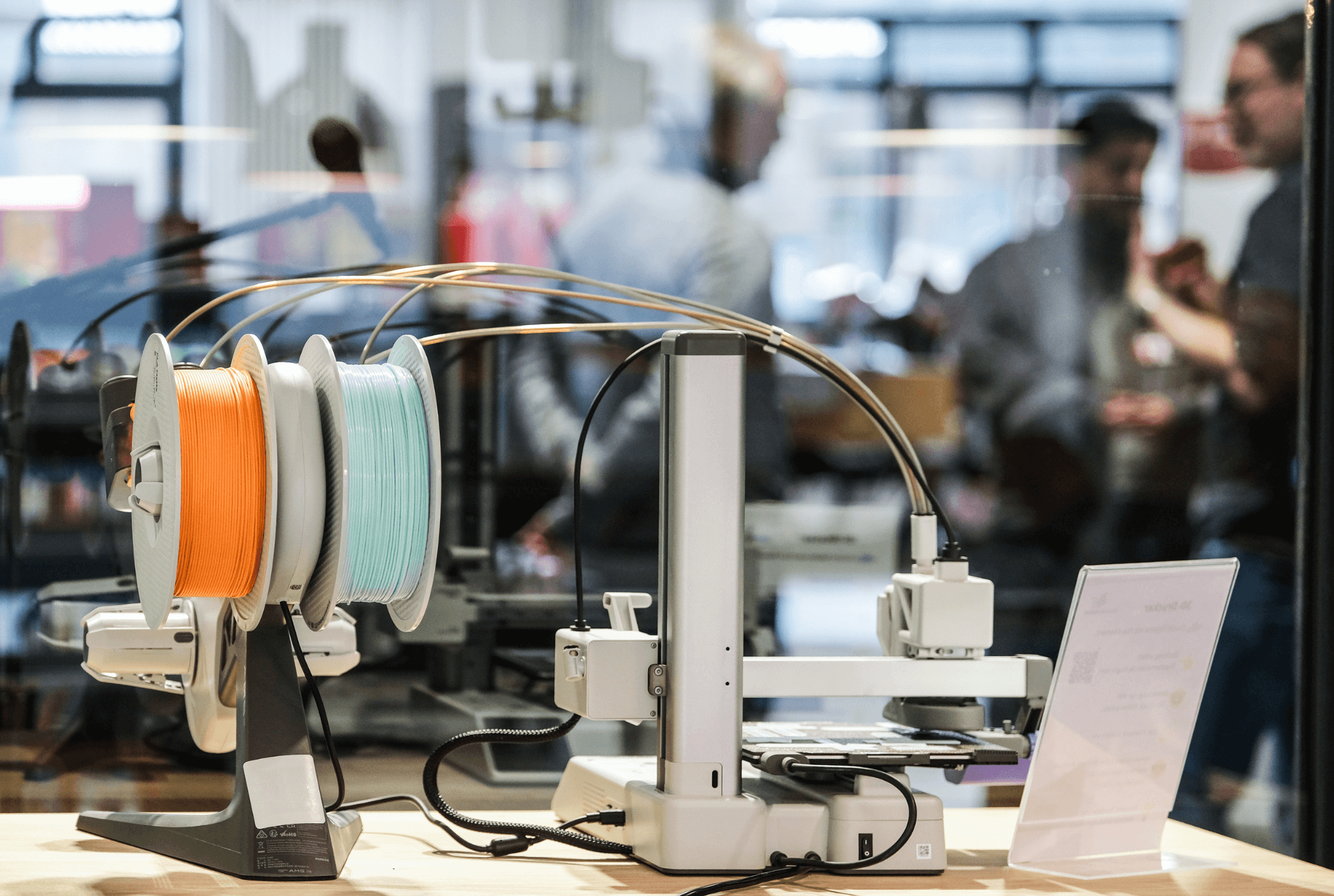 Im Vordergrund ist ein Gerät des Makerlab, im Hintergrund sind verschwommen einige Menschen zu sehen