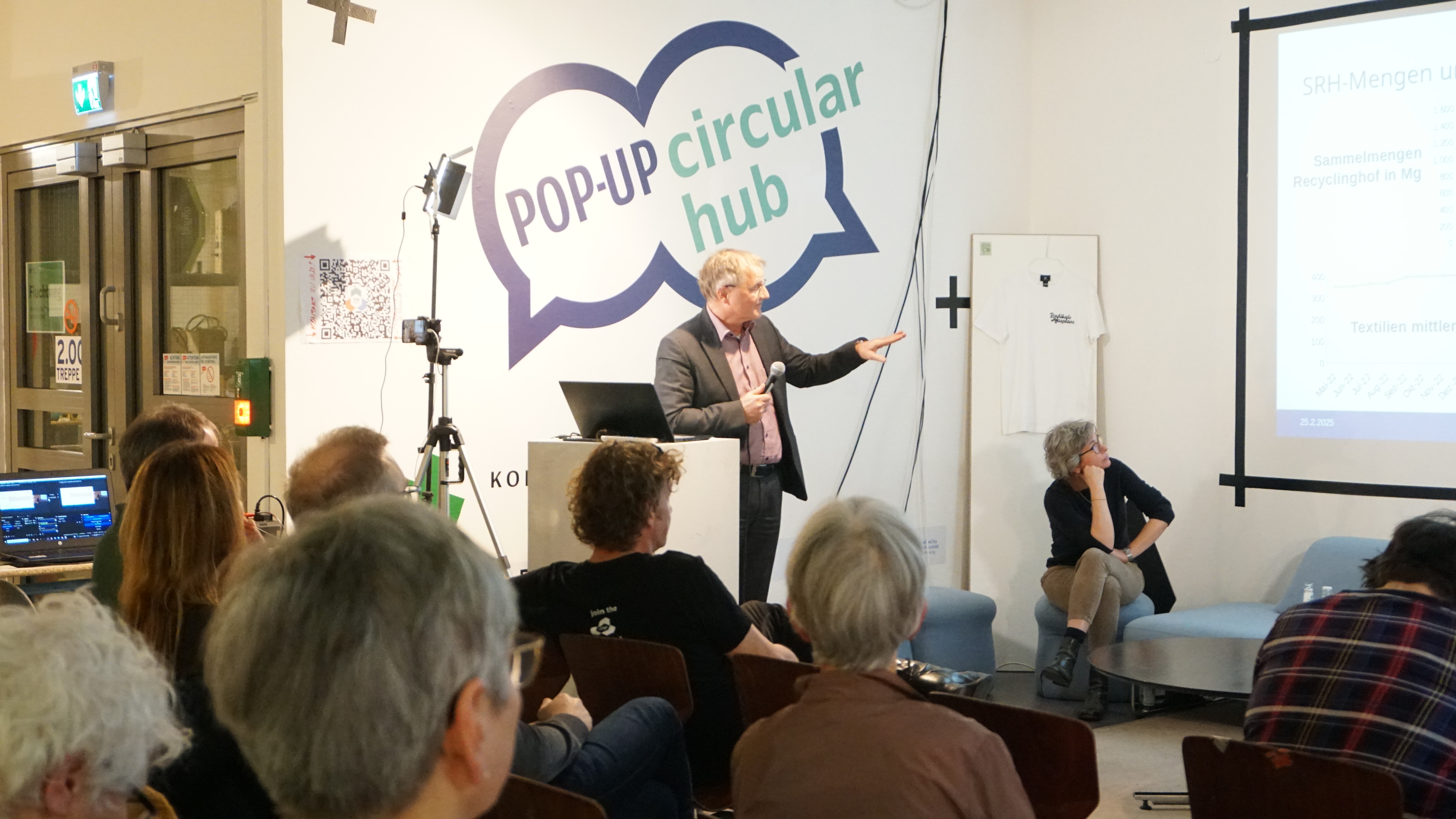 Mann am Rednerpult zeigt eine Präsentation