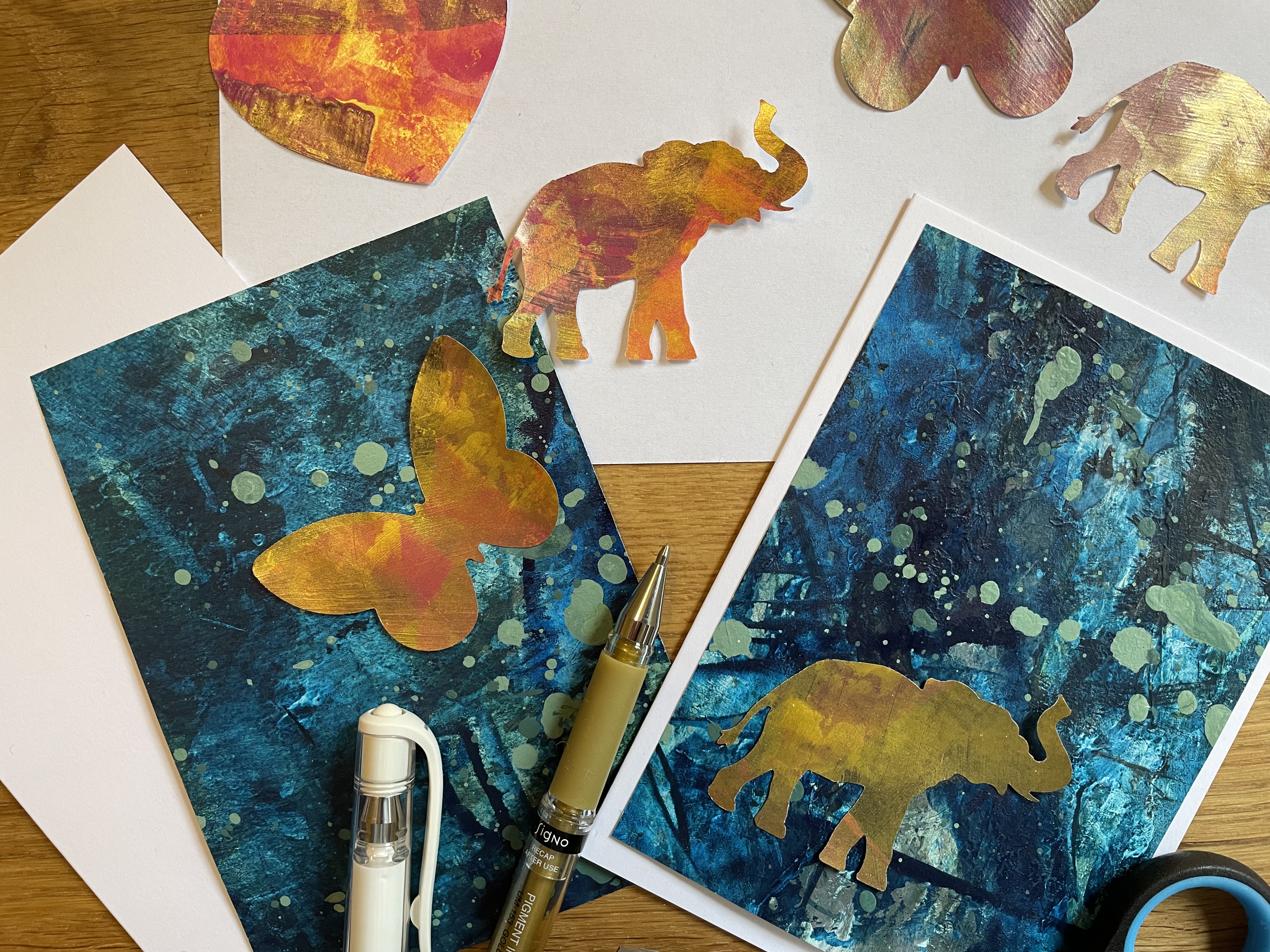 Zwei blaue Grußkarten mit goldenem Schmetterling und Elefant
