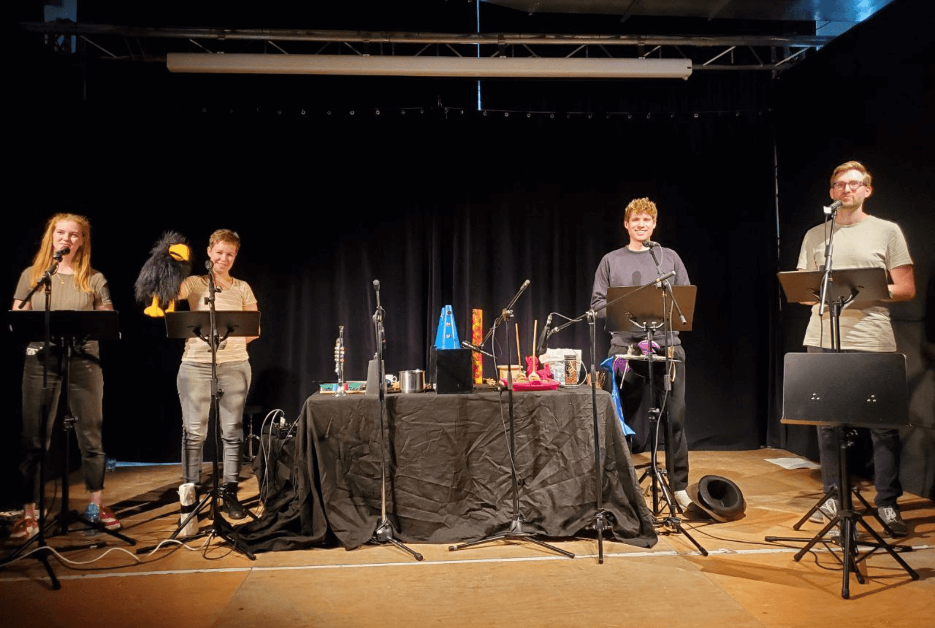Vier Personen führen auf einer Bühne ein Hörspiel auf.